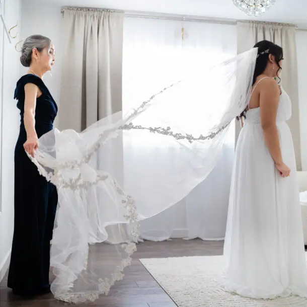 A woman and her mother are holding up their wedding veil.