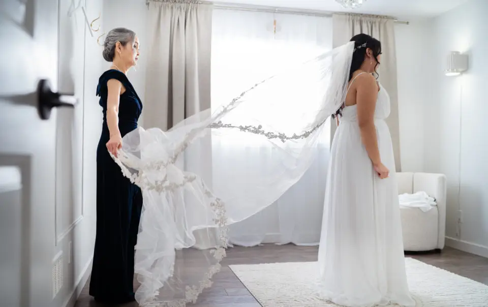 A woman and her mother are holding up their wedding veil.