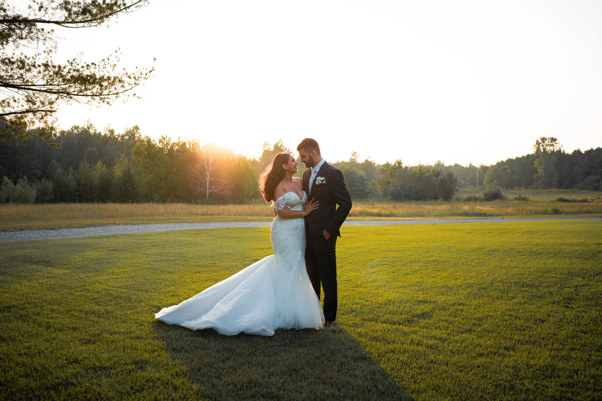 A bride and groom pose for the camera in their wedding dress.