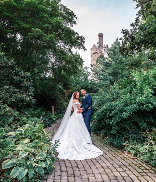 A bride and groom pose for a picture on the path.