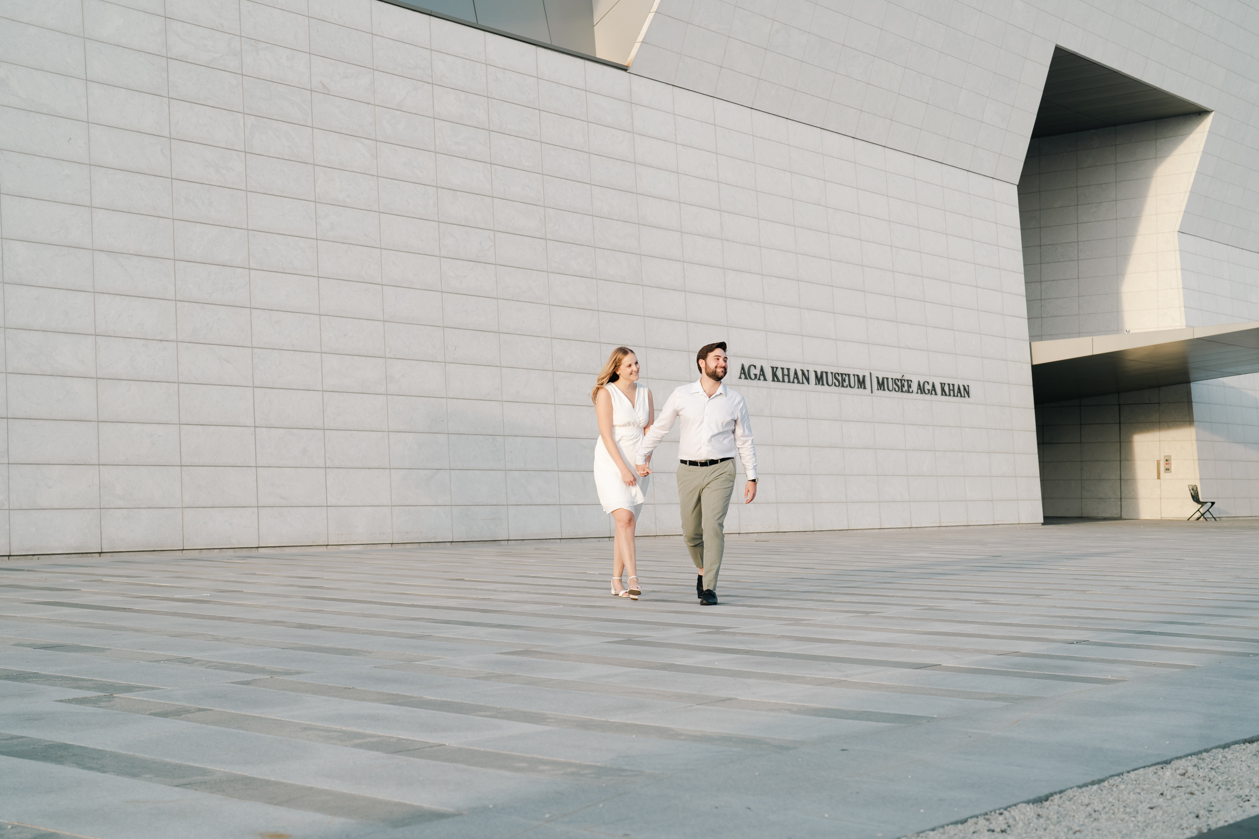 A man and woman holding hands while walking down the sidewalk.